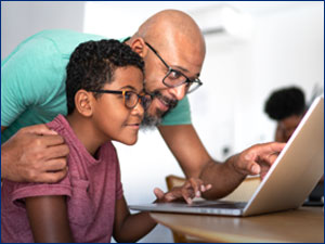 Man showing young son something on laptop