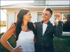 woman and man standing in front of home and holding keys