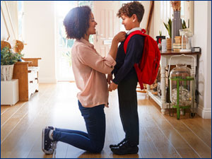 child wearing a backpack with woman fixing the child's collar