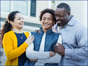 man and woman hugging child in front of home