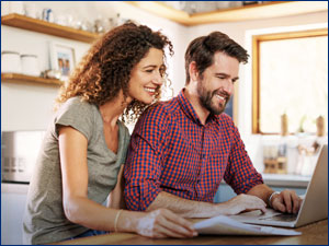 man and woman looking at laptop with papers in front of them