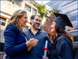 man and woman smiling with person wearing cap and gown holding a diploma