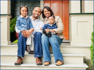 man woman and two children sitting on steps in front of home