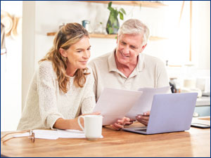 man and woman sitting at table looking at laptop