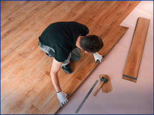 Man installing laminate flooring in a home