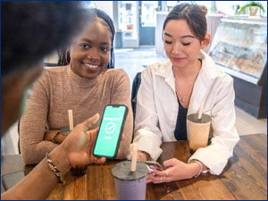 three people sitting at table looking at mobile phone