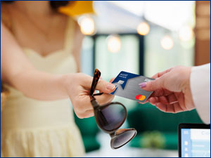 person handing another person their RBFCU World Cash Back Mastercard credit card