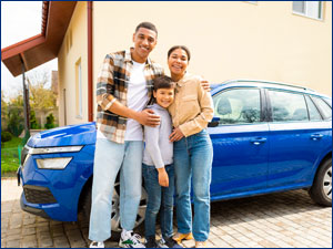 Family smiling in front of a car.