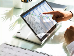 Hand pointing at a spreadsheet on a tablet.