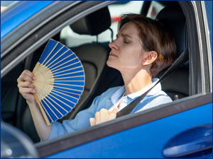 Woman fanning herself while sitting in a car