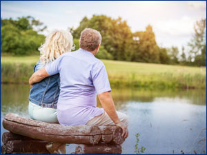 Couple sitting on bench looking at a lake. 