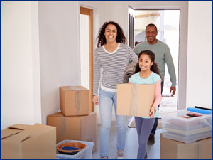 Girl carrying a box with her parents while moving into a house