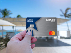Hand holding the RBFCU World Cash Back Mastercard in from of a beach.
