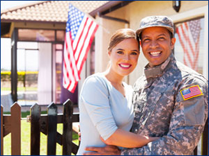 Solider smiling with a woman outside a home. 