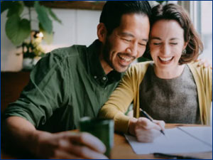 Man and woman smiling while filling out paperwork