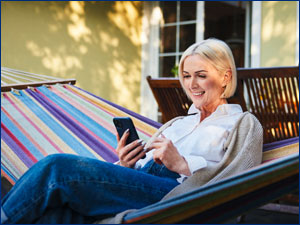 Woman looking at phone while sitting on a hammock