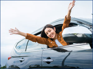 Woman smiling while hanging her head out a car window. 