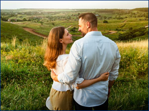 Woman and man hugging while looking at open land