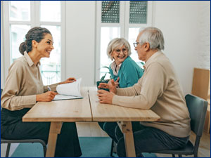 man and woman looking at each other while sitting at a table in front of a woman going through documents