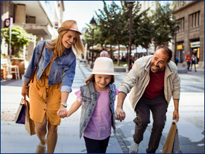 man woman and child walking in outdoor mall holding shopping bags