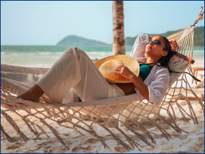 Woman laying on a hammock on the beach.