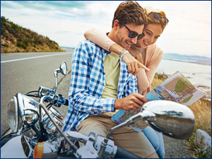 Couple sitting on a motorcycle pointing at a map. 