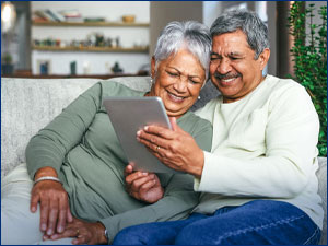Couple smiling at a tablet. 