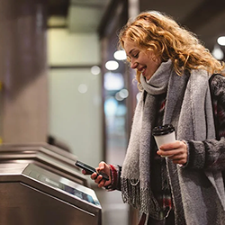Young woman checking out at metro station using mobile phone