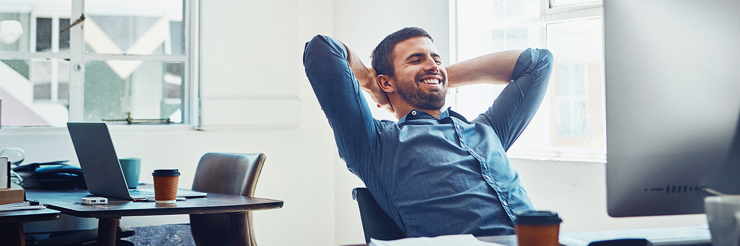 Business Accounts Man leaning back in his chair at his desk at work