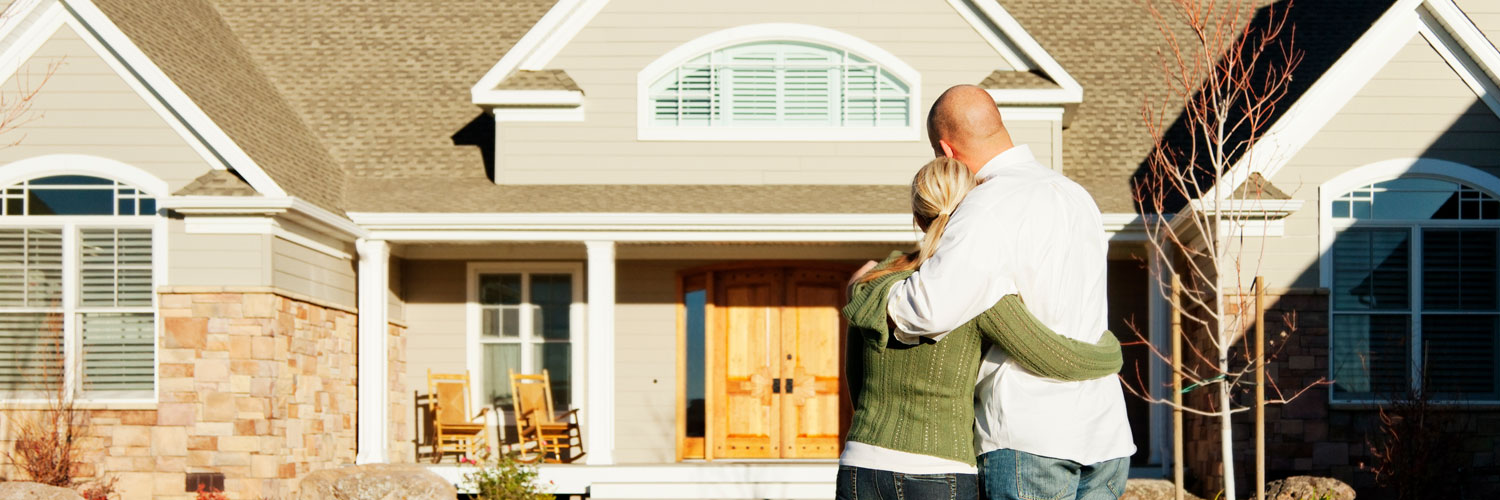 FHA-and-VA-Loans-Hero Couple hugging and looking at their home