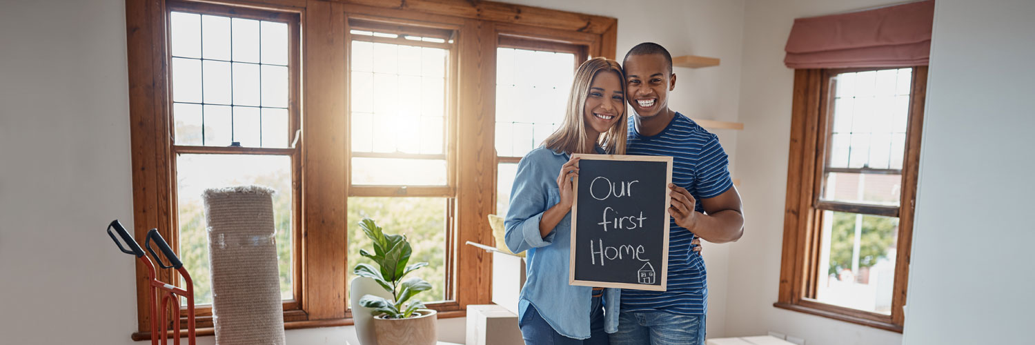 First-Time-Homebuyers-Hero A couple holding a sign that reads "our first home"