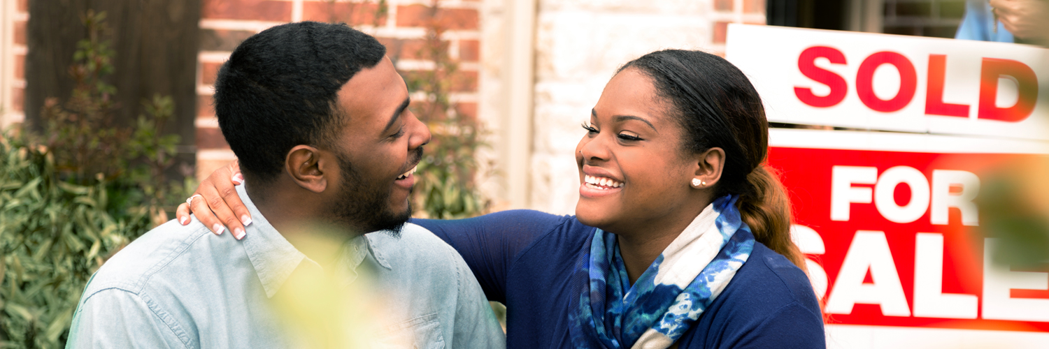 Title-Insurance-Hero-Image A couple in front of a "sold" sign at their new home