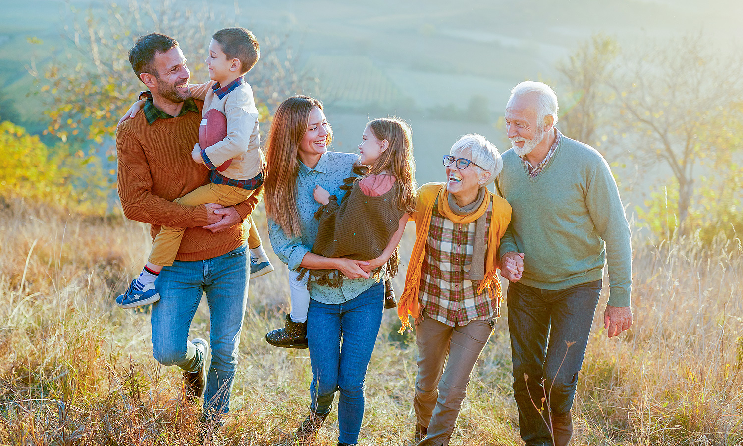 Multigenerational family hiking through field