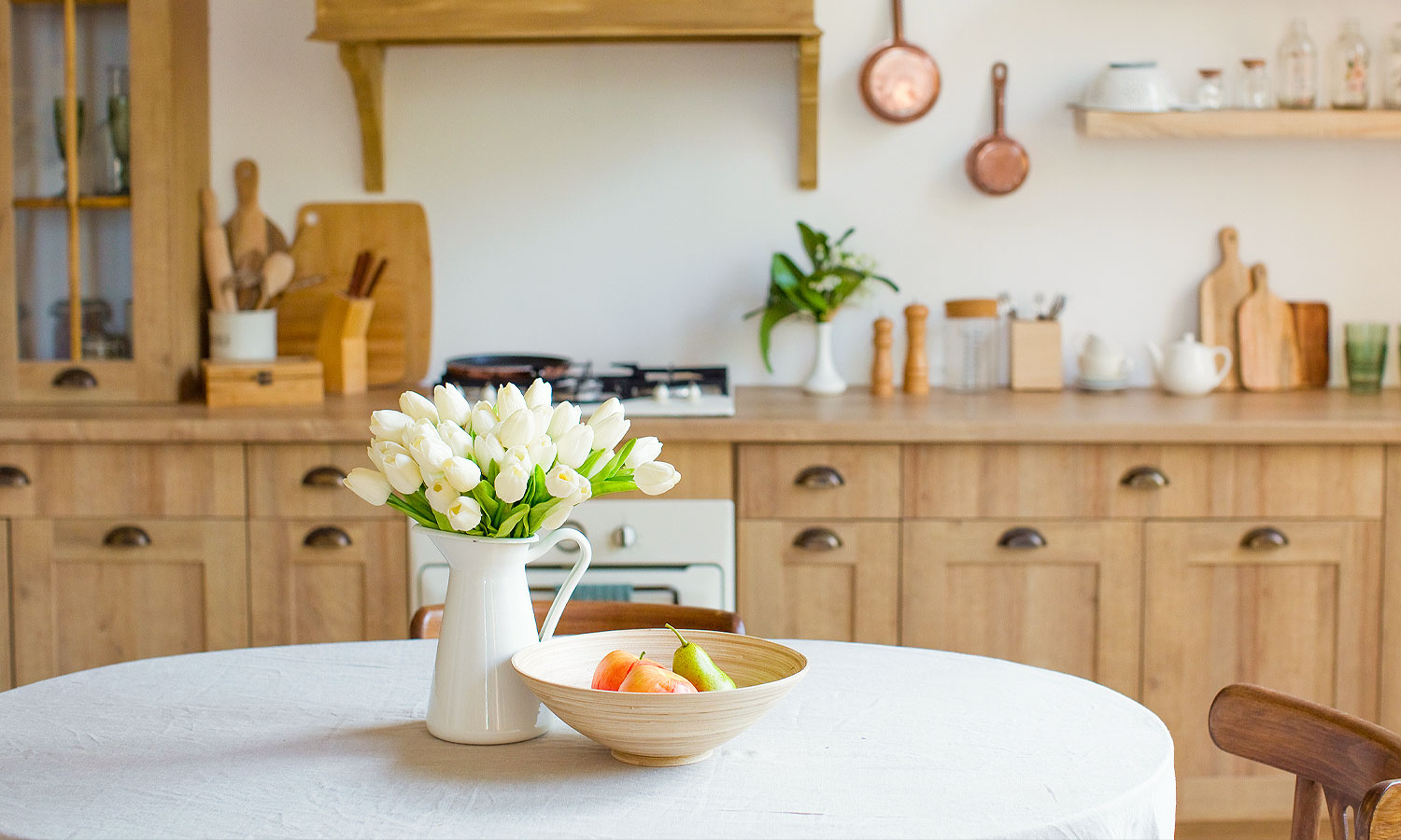 Pitcher with tulips on table in neat kitchen