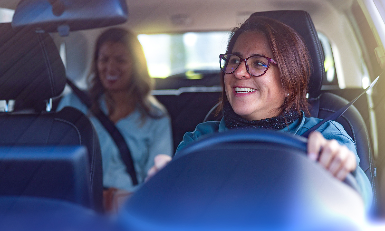 woman driving car with a passenger in the backseat