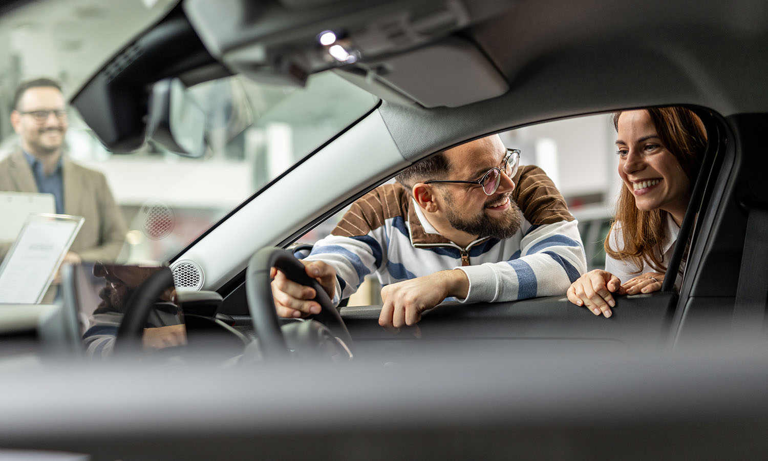 woman enjoying new car hugging steering wheel sitting inside