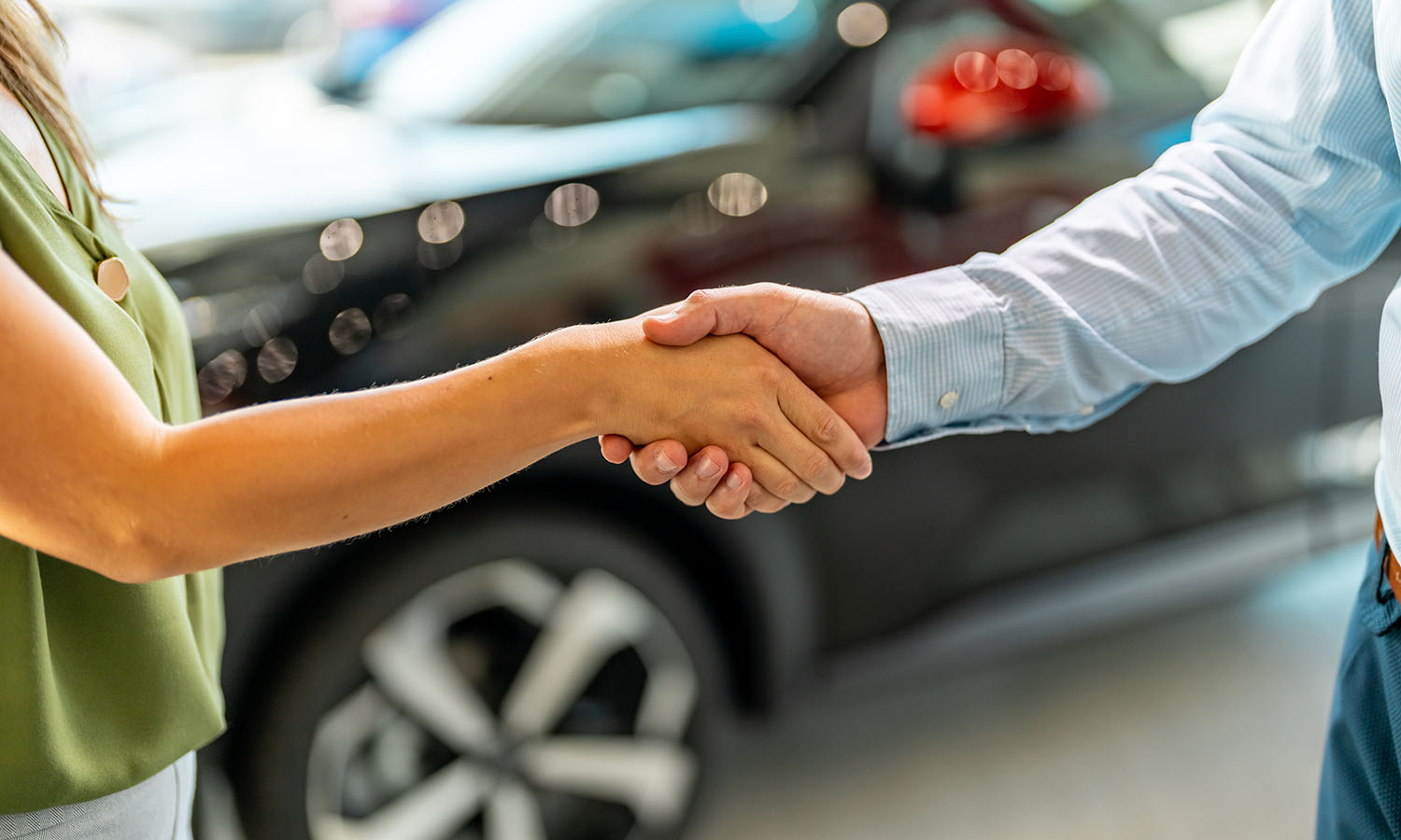 Handshake between two business people in a car showroom