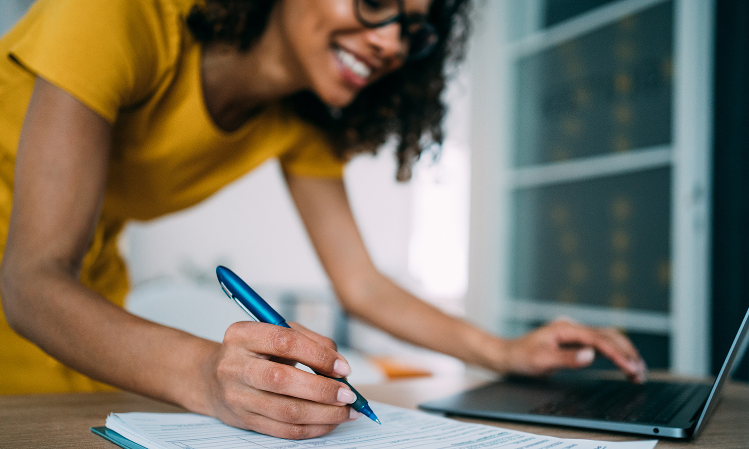 Woman taking notes while using a laptop