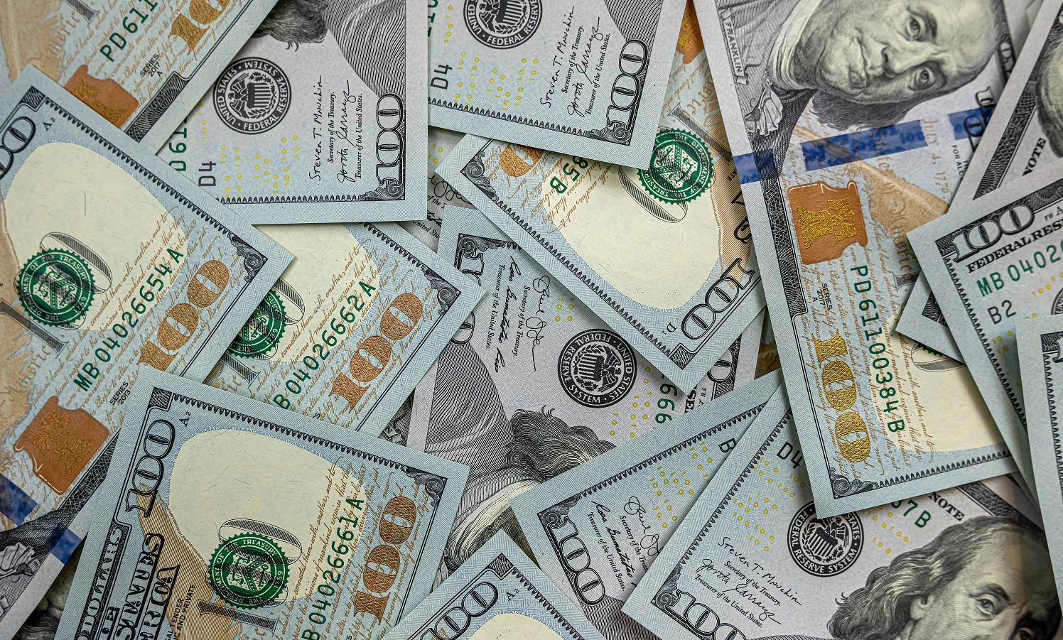 Hundred dollar bills spread out on a surface
