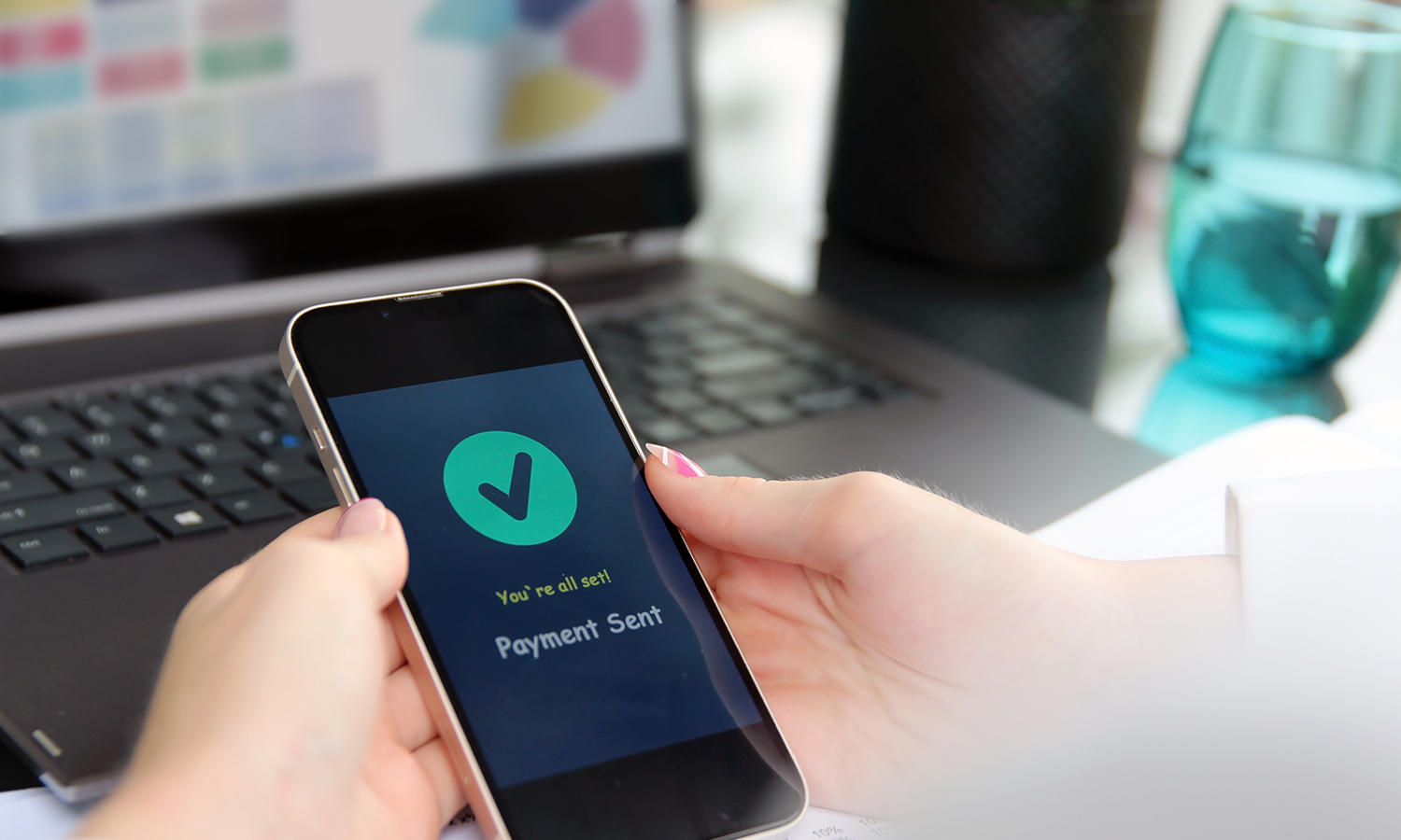 Payment sent on smartphone while reviewing credit score graphs on laptop
