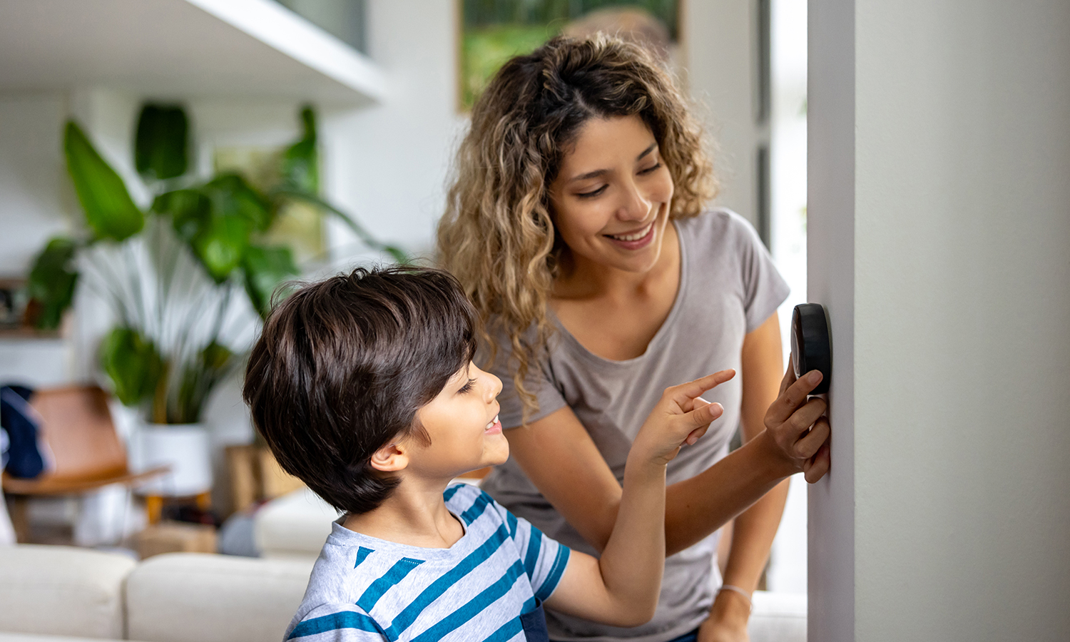Woman and boy adjust smart thermostat