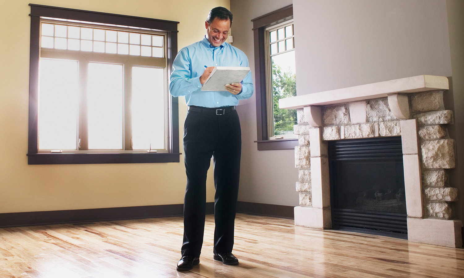 Man with clipboard taking notes in empty house