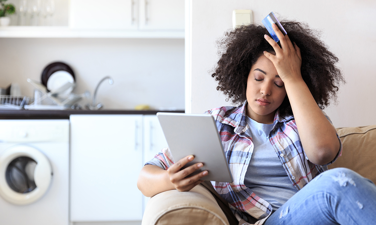 Woman looking frustrated while holding credit card and tablet