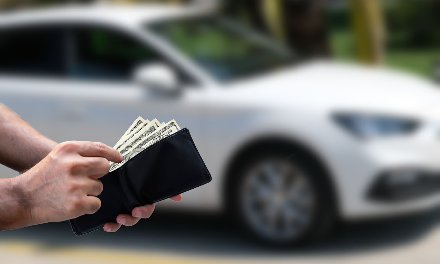 hand paying cash in front of car