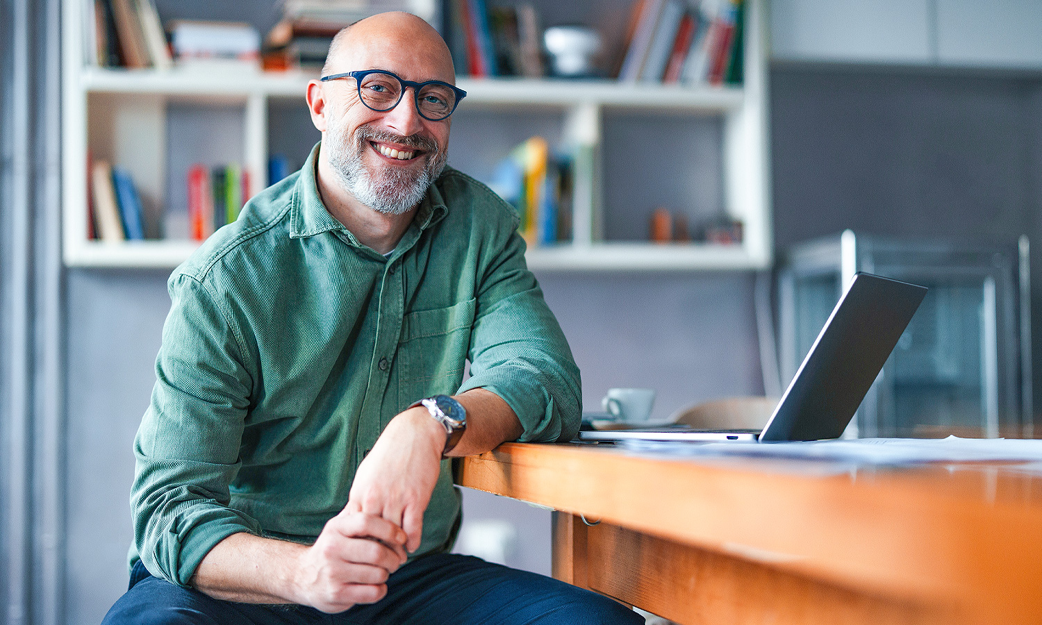 man sitting at desk in front of laptop