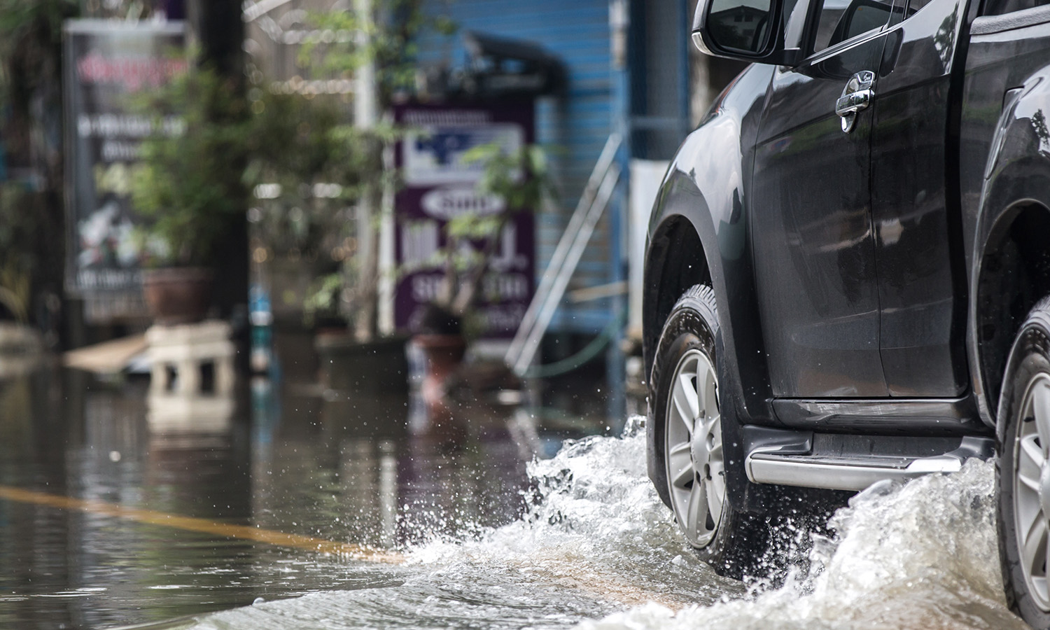 black car driving through the rain and splashing water