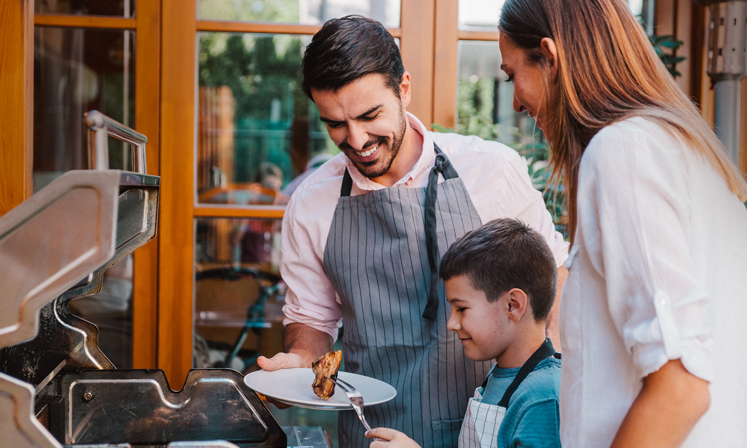 man woman and child cooking food on the grill