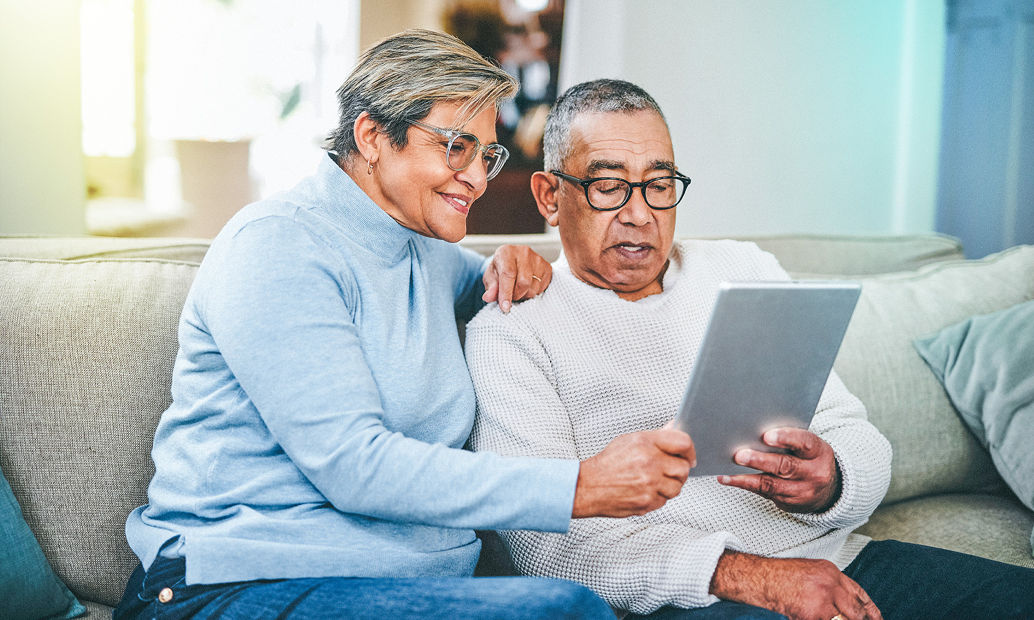 woman and man sitting on couch reading a tablet