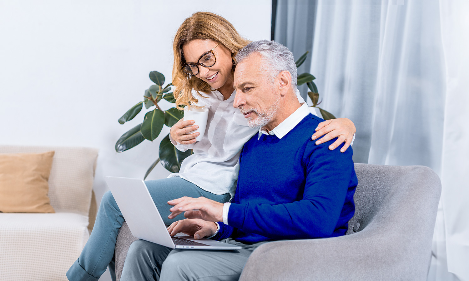 woman and man sitting on chair looking at a laptop