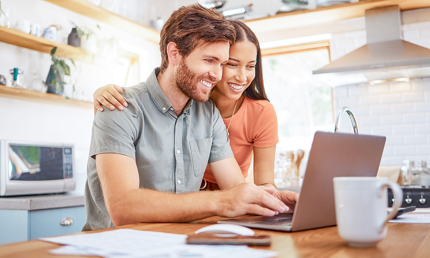 man and woman sitting in the kitchen looking at a laptop